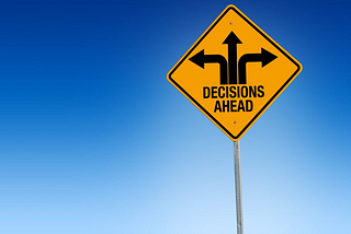 A traffic sign with 3 arrows in different directions with caption “Decisions Ahead”