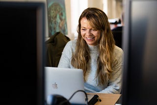 A female looking at her laptop and smiling.