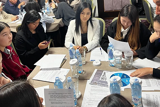 Young people sitting around a table with papers and water bottles.