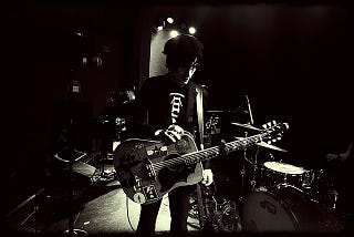 Jesse Malin in concert holding a guitar