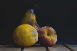 Three fruits that are rotting and molding.