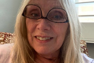 Blonde author, smiling while wearing her glasses upside down.