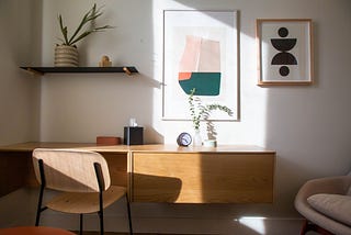 A minimal, modern desk with well-lit art above it.