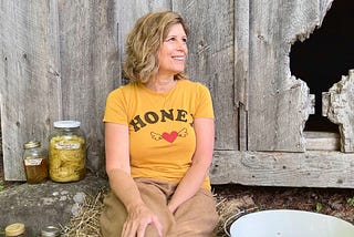 Woman sitting in front of an old barn smiling.