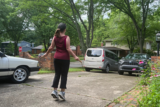 a woman jumping rope on a driveway