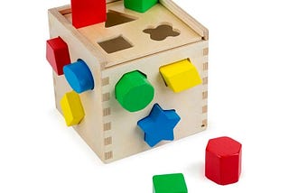 the classic “pegs into holes” kiddie game, a wooden box with holes having different shapes and different colored pegs, some of them already fitted into some of the holes