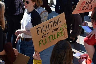 A sign reads Fighting for our future. Be for rather than against.