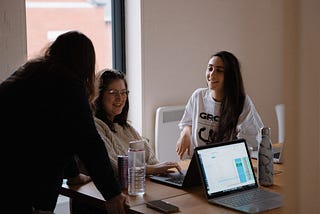 Three colleagues in a digital product studio have a conversation about strategies for digital product development around a table.