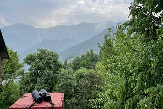 A pair of binoculars on a red-brick pillar of a house overlooking the Dhauladhars, Himalayas