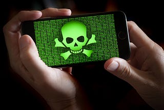 A smartphone held in hands showing a green colored skull and bones symbol.