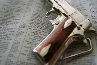 A photo of a toy gun lying on top of an open Bible.