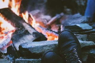 Boots propped up on a rock while gathered around a campfire.