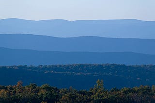 Photo of the Appalachian mountains. The mountains are layered and appear in different shades of blue from the foreground to the background.