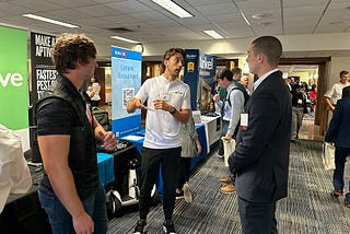 Three men talk to another during a career fair.