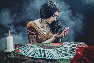 A psychic has tarot cards fanned out in front of her as she examines the one in her hand