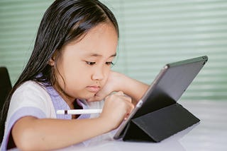 A young learner stares sadly at a tablet holding the e-pen.