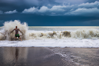 a DALL-E created image of person in fear looking at the incoming tide and turning to run fast but being caught by the water