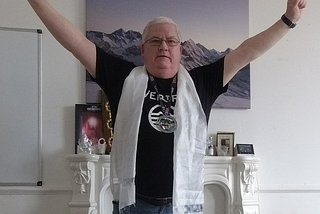 Man standing hands raised wearing scarf and medal.