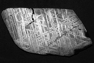 his is a macro photograph of the Muonionalusta meteorite in the ground and etched condition showing the Wedmanstatten structure. The diagonal line in the lower right hand zone of the specimen is a prior-Taenite grain boundary.