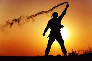 A soldier signaling with a flare in a sunset background