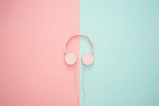 Pink headphones on a pastel background. Background is split in half vertically, left is pink, right is green