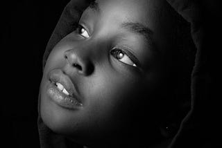 black and white closeup photo of a girl looking up and to the side, black background