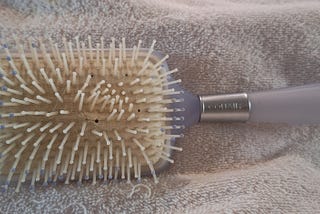 My childhood hairbrush, light purple, large brush area, rectangle shaped, bristles are looking sad due to age, light purple handle with gray metal part.