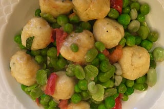 The peas and dumplings on a dinner plate.