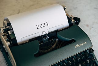 An antique typewriter with a written “2021” paper