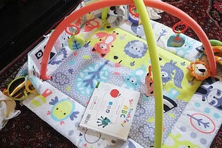 A baby’s play mat, covered in colourful animal pictures, toys and an ABC book
