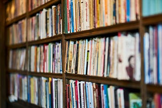 Brown wooden bookshelves filled with a variety of paperback books.