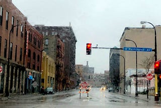 Desolate, rainy, empty city street, with red light and Do Not Enter signs.