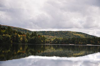 Clouds, forested hills, and a lake.