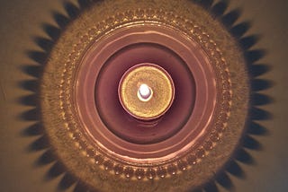 A candle in a decorative holder casting an intriguing shadow.
