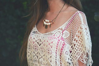 Woman in white and red floral shirt wearing a necklace.