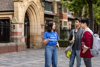 A student ambassador chats with two students outside of the Great Hall.