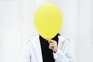 Person with balloon over their face.