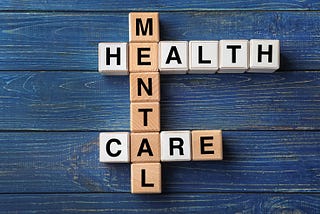 Cubes composed words MENTAL HEALTH CARE on color wooden table