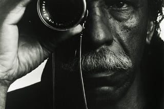 Elderly Gordon Parks holding a camera lens up to his eye