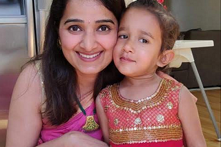 Neha stands in her kitchen next to her adorable daughter!