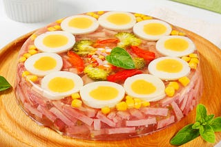 Geletin salad with eggs, ham and vegetables on a plate