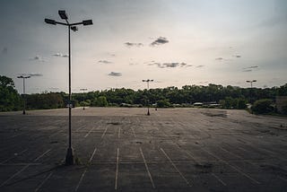 Empty parking lot surrounded by trees.
