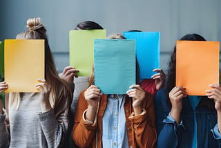 Five people with colored pieces of paper covering their faces