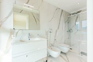 A bathroom with white marble as a theme.