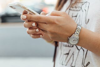 A young woman looking at a phone in her hands.