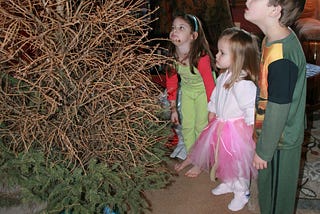 three sad young children gaze that their dead Christmas tree