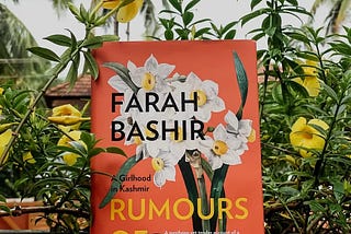 The book ‘Rumours of Spring’ against the backdrop of some allamanda flowers.