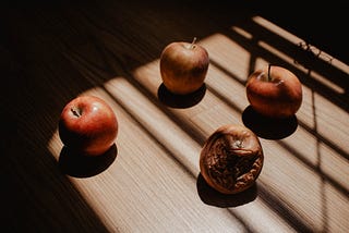 4 apples in a circle, the one on the left at 9pm looking healthy, the one on 12 and 3pm sligthly unpleasant and the apple at 6pm rotten and decomposing.