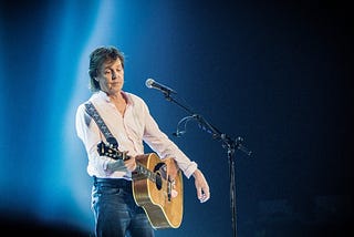 Paul McCartney playing guitar on stage