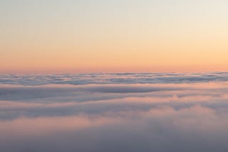 An orange and blue sky sits above white clouds.